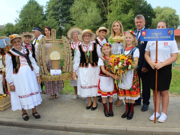 Dożynki,Skierbieszów, grupa seniorów, uczestników dożynek, w środku grupy wieniec, po prawej kobieta trzymająca chleb.